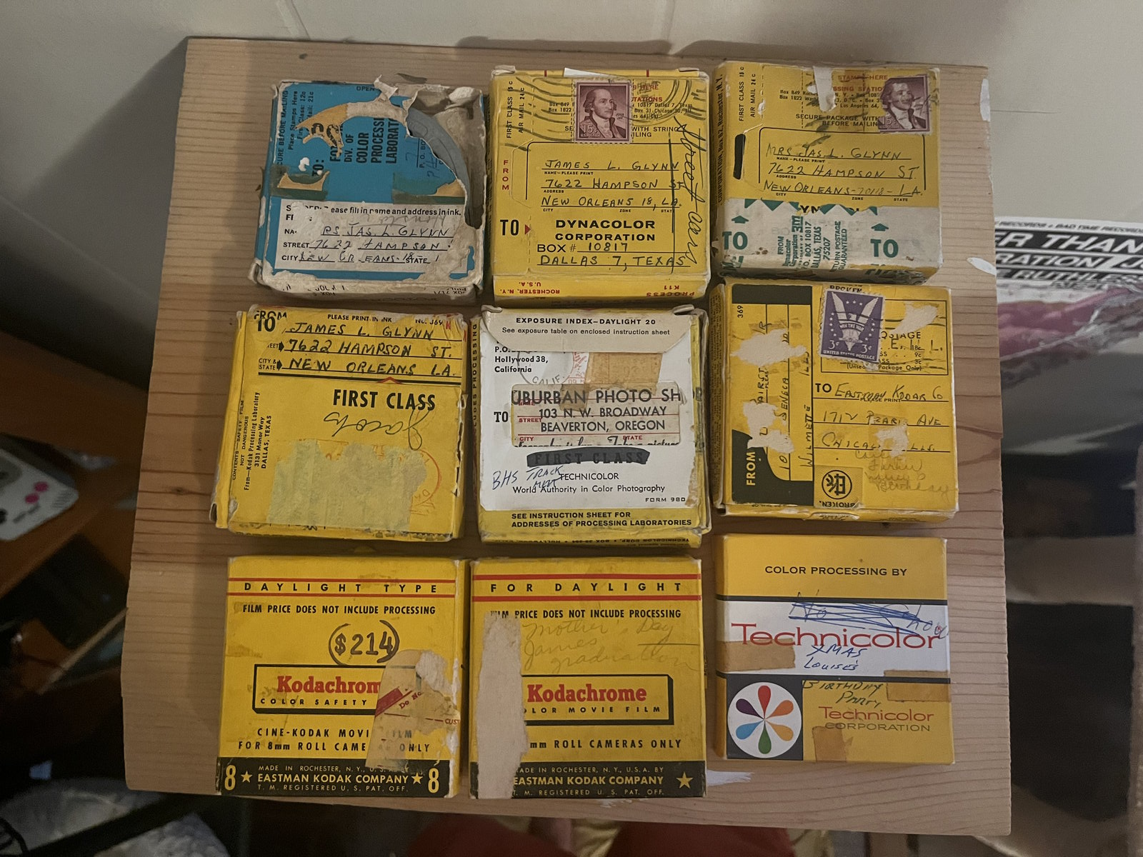 Seen from above: a dozen yellow Kodachrome and Ektachrome processing boxes packed into a shallow wooden tray, most carrying handwritten notes.