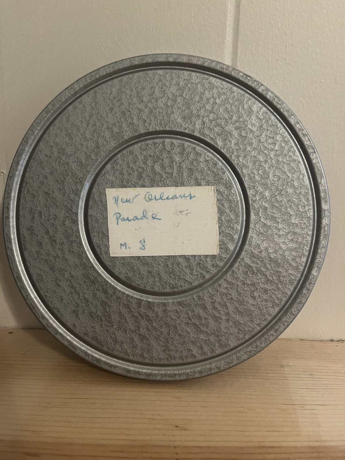 A single hammered-grey film can with a small hand-lettered label reading New Orleans Parade.
