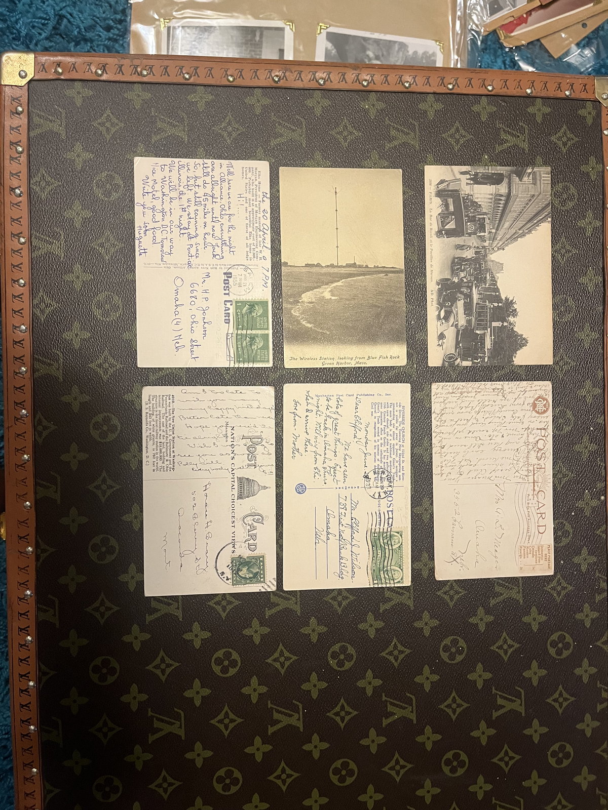 Vintage postcards laid out in a grid on a monogrammed case.