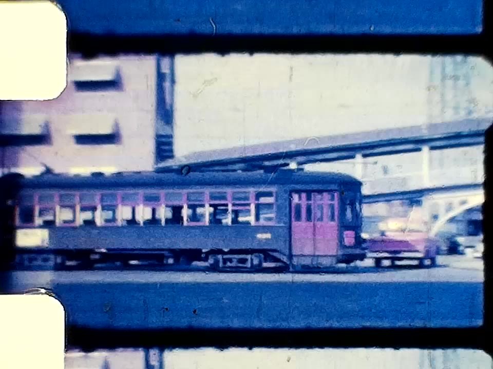 A frame of digitized colour footage: a maroon streetcar on Canal Street, with the film's sprocket edge visible.
