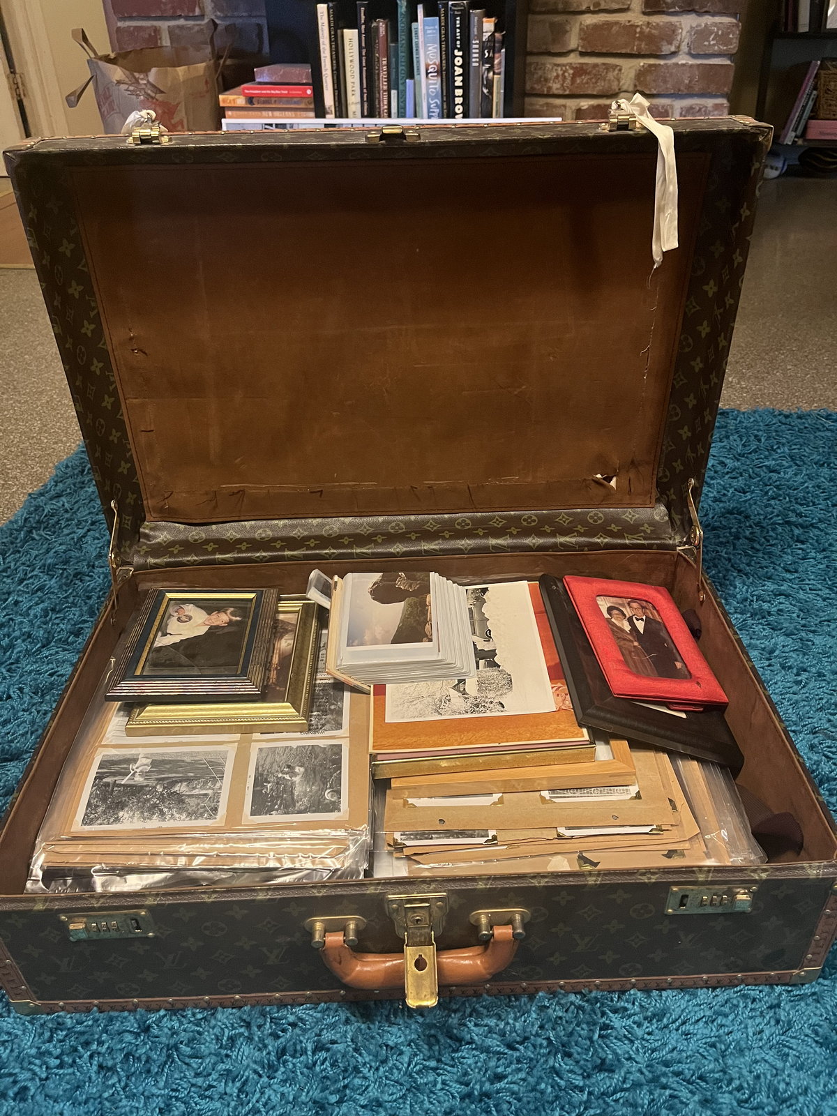 An open steamer trunk packed with boxed slides, loose prints, and a framed photograph — a family collection as it usually arrives.